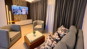 En moderne stue med sofa, to lænestole, sofabord og fjernsyn monteret på væggen.