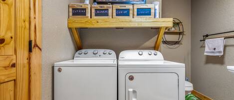 A laundry area with two washing machines, a shelf with labeled boxes, and a wooden door.