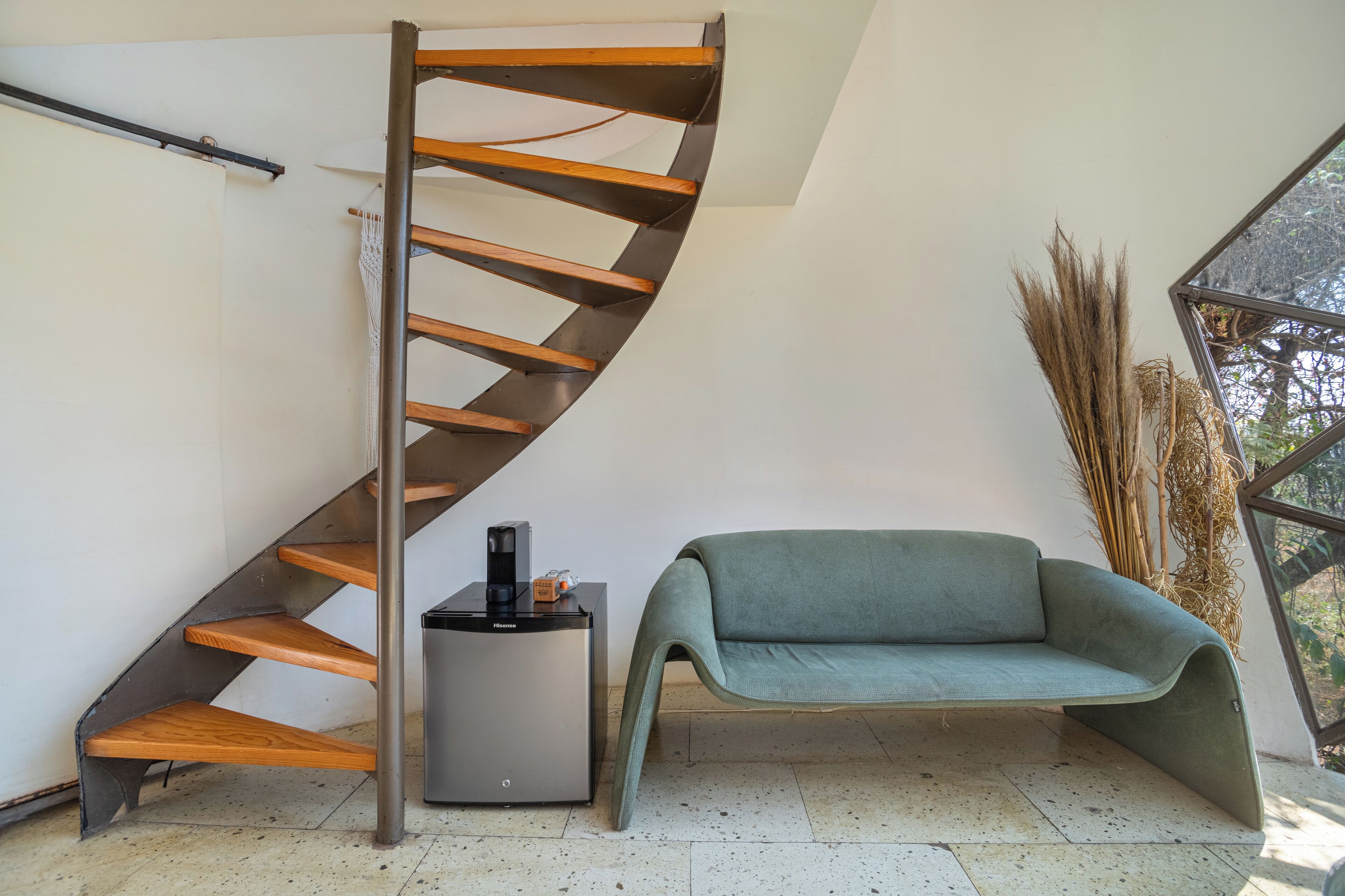 A spiral staircase with wooden steps and a modern coffee machine on a small table beside it.