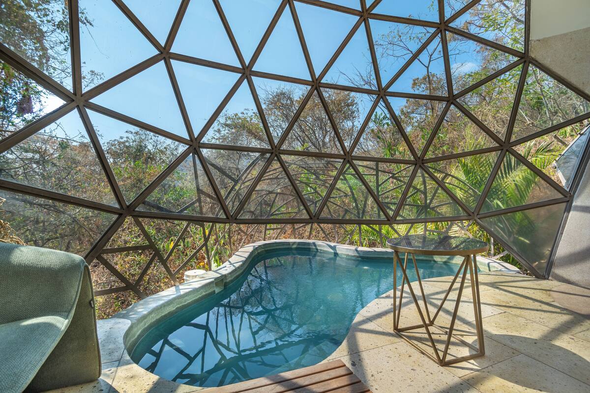Estructura de cúpula geodésica con piscina y zona de estar.