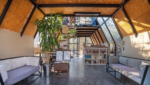 A cozy, modern interior with a high ceiling, a bookshelf, two sofas, and a hanging plant. - Bosque Geométrico (Tepoztlán)