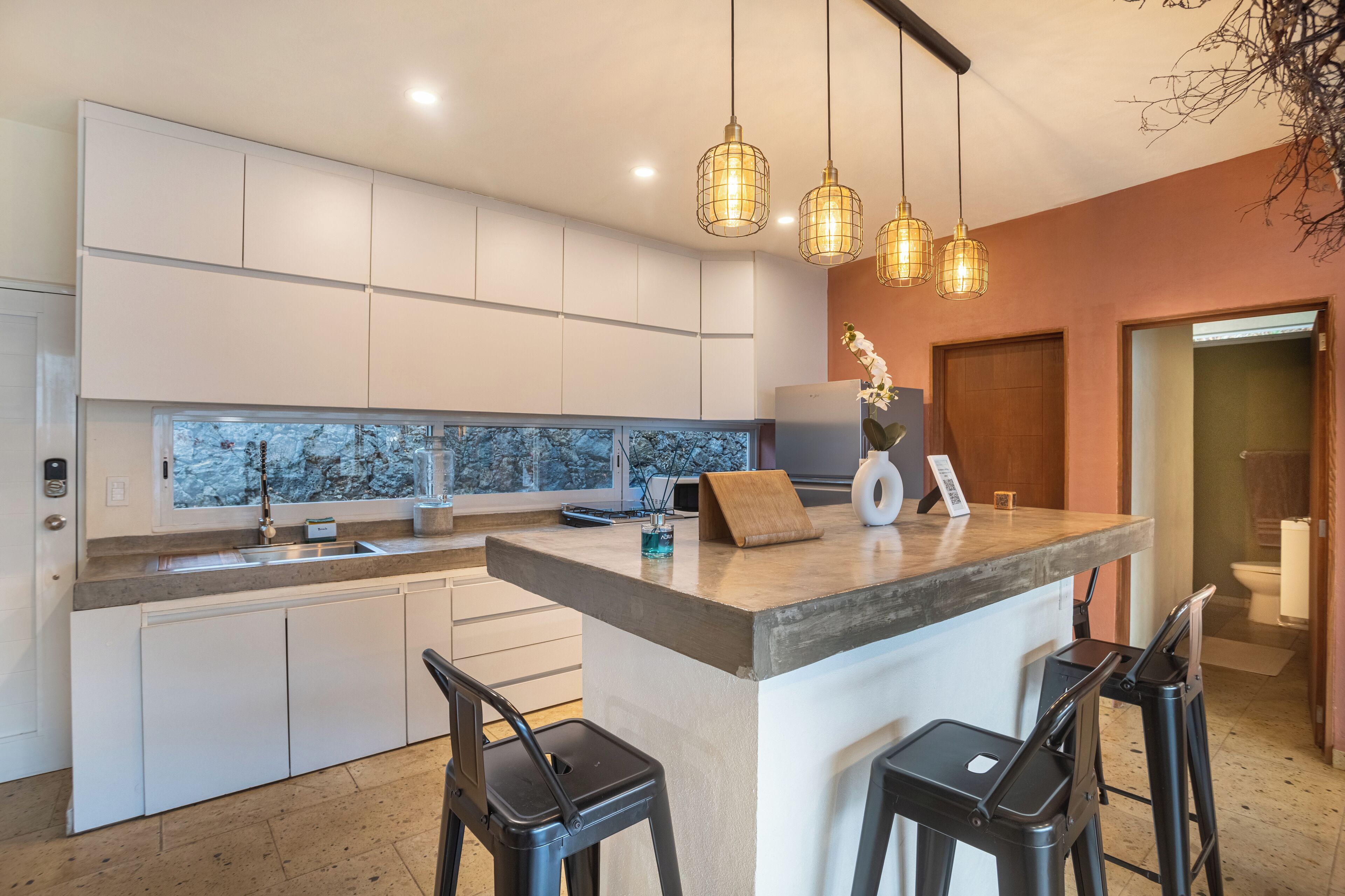 A modern kitchen with white cabinets, a marble backsplash, and pendant lighting.