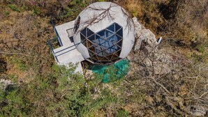 A spherical building with a geometric window design, surrounded by natural vegetation. - Bosque Geométrico (Tepoztlán)
