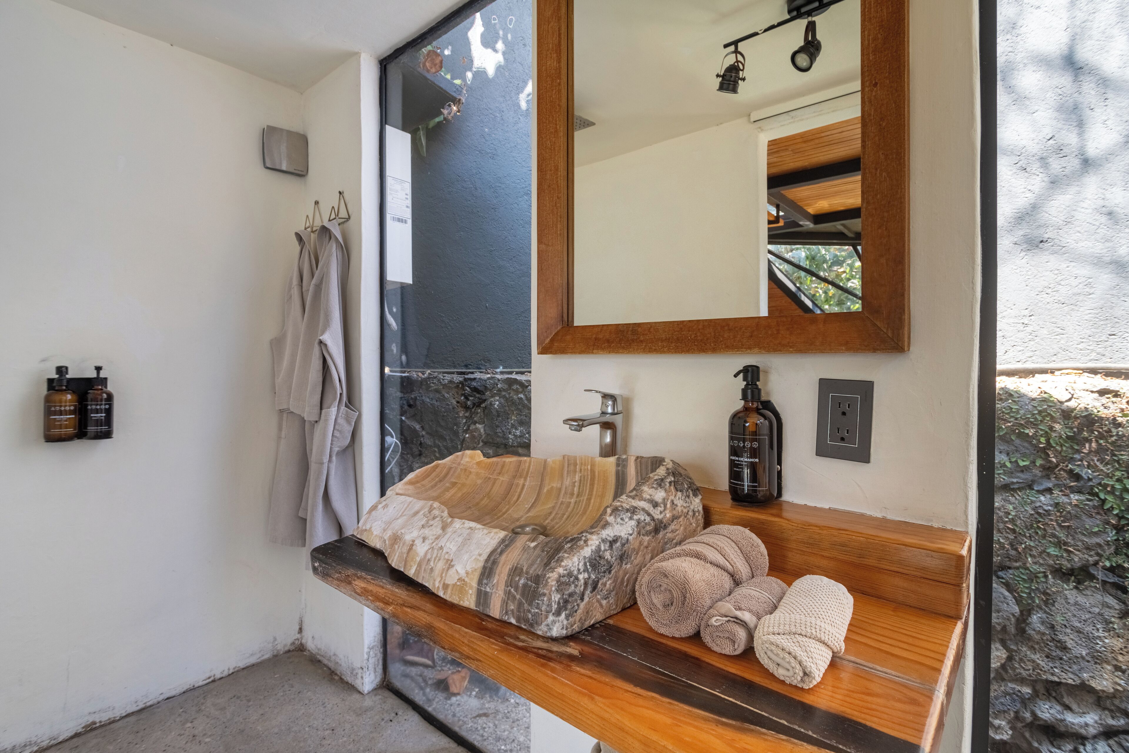 A bathroom with a stone sink, wooden vanity, and a large mirror.