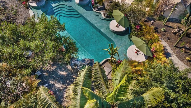 An aerial view of a resort with a swimming pool, surrounded by lush vegetation and unique architectural structures. - Bosque Geométrico (Tepoztlán)