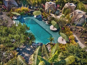An aerial view of a resort with a swimming pool, surrounded by lush vegetation and unique architectural structures. - Bosque Geométrico (Tepoztlán)