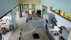 A modern kitchen with a gas stove, a sink, and a dining area with a table and chairs. - Casa Mono Alegre (Tres Rios)