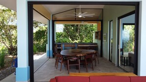 An open-plan living area with a dining table, chairs, and a red sofa. - Casa Mono Alegre (Tres Rios)