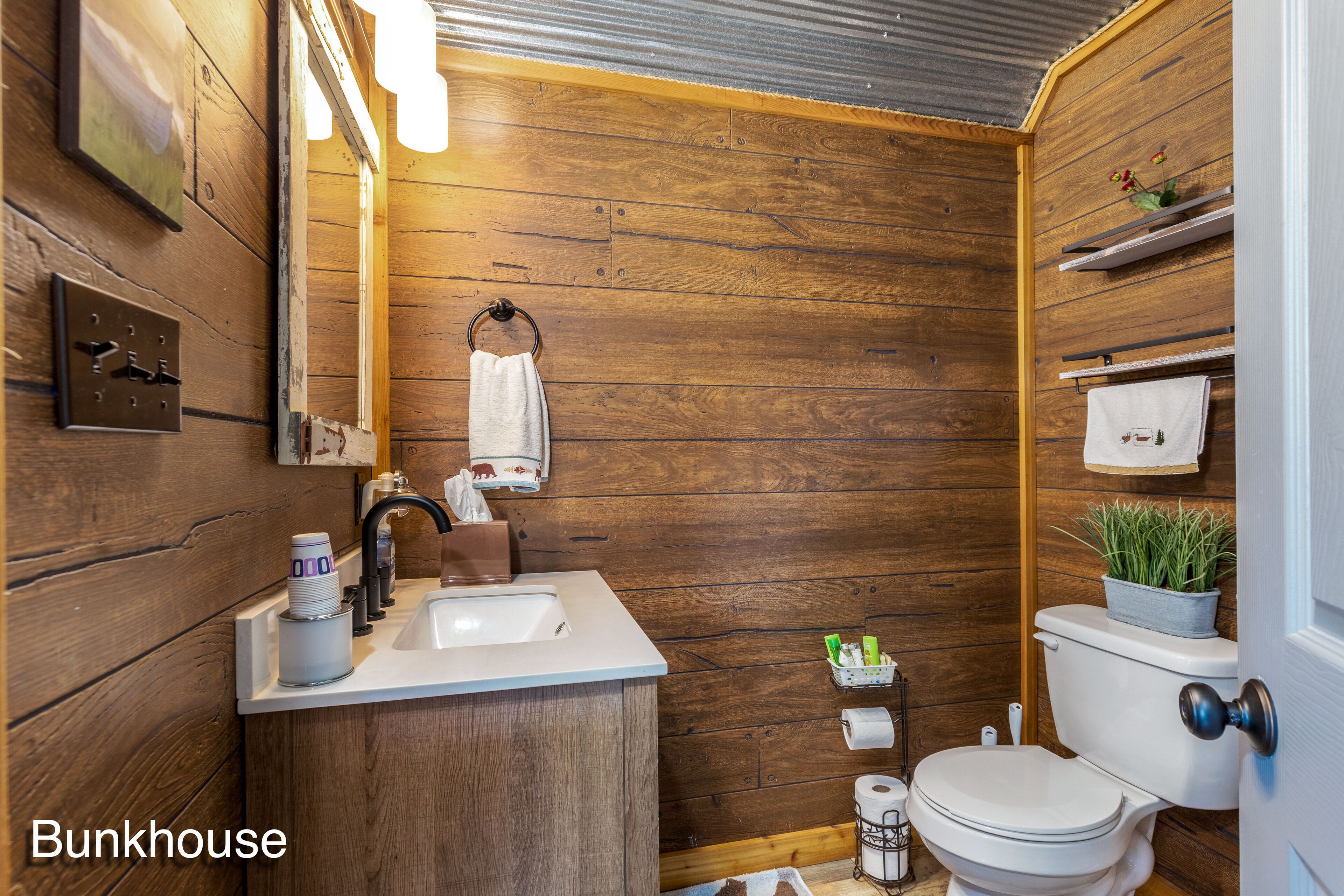 Un bagno con pareti in legno, un lavandino, un water e uno specchio.