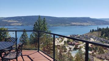 A balcony with a table and chairs overlooking a lake and residential area.
