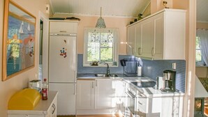 A kitchen with white cabinets, a stainless steel sink, and a window with a floral curtain. - Amazing home in Drøbak with kitchen (Drøbak)