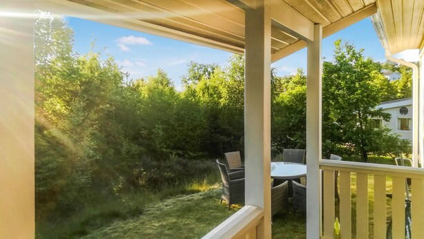 A covered outdoor area with a table and chairs, surrounded by greenery and a view of a house. - Amazing home in Drøbak with kitchen (Drøbak)