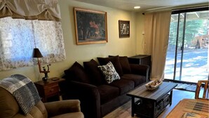 Un salon comprenant un canapé, un fauteuil, une table basse et une cheminée.