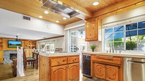A spacious kitchen with wooden cabinets, a central island, and a large window providing natural light. - Charming Country-Style Home with Backyard Oasis! (Laguna Hills)