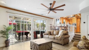 A spacious living room with a pool table, a large window, and a ceiling fan. - Charming Country-Style Home with Backyard Oasis! (Laguna Hills)