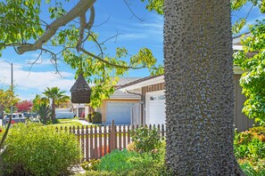 Stroll through the beautifully maintained front yard, surrounded by lush shrubs and a mature tree.