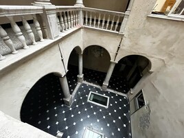 Un patio con suelo de baldosas, balaustradas blancas y arcos.
