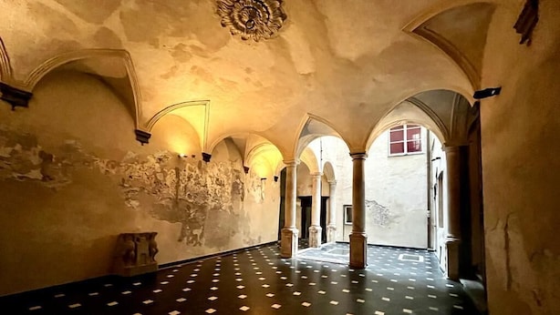 Um interior com tetos abobadados, um chão estampado e um pilar central.