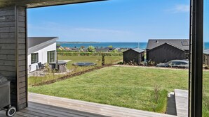 Une maison moderne dotée d’une grande terrasse, d’un jacuzzi et offrant une vue sur la mer.
