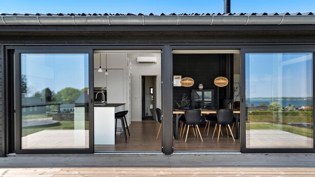 Une cuisine moderne avec un coin repas, de grandes portes-fenêtres coulissantes et une vue sur l’extérieur.