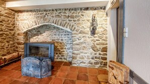 Une cheminée en pierre avec un paravent en métal, une enseigne en bois et un sol carrelé.