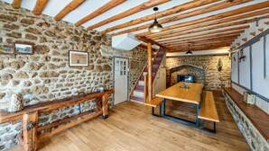 Une cuisine rustique avec des murs en pierre, des poutres en bois, une cheminée en pierre et un banc en bois.
