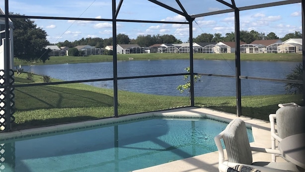 Piscina cubierta al aire libre con vistas a un lago y casas al fondo.