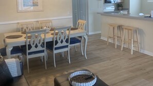Una sala de estar moderna con comedor, cocina y un sofá de cuero negro.