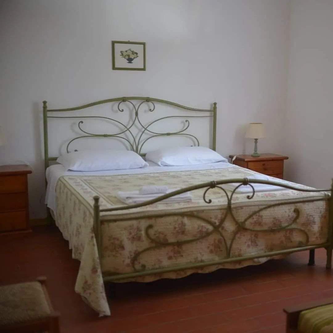 A single bed with a floral-patterned bedspread and white pillows, flanked by two wooden nightstands with lamps.