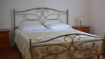 A single bed with a floral-patterned bedspread and white pillows, flanked by two wooden nightstands with lamps.
