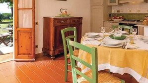 Un comedor con una mesa preparada para dos, un armario de madera y un cuadro en la pared.