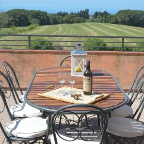 A table with a bottle of wine, glasses, and a lantern on a terrace with a view of a golf course. - AGRITURISMO LE CERBONCHE (Rosignano Marittimo)