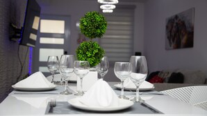 A dining table set with white plates, glasses, and a centerpiece of green spherical plants.