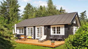 Een houten hut met een terras, ramen met witte kozijnen en een donker dak.