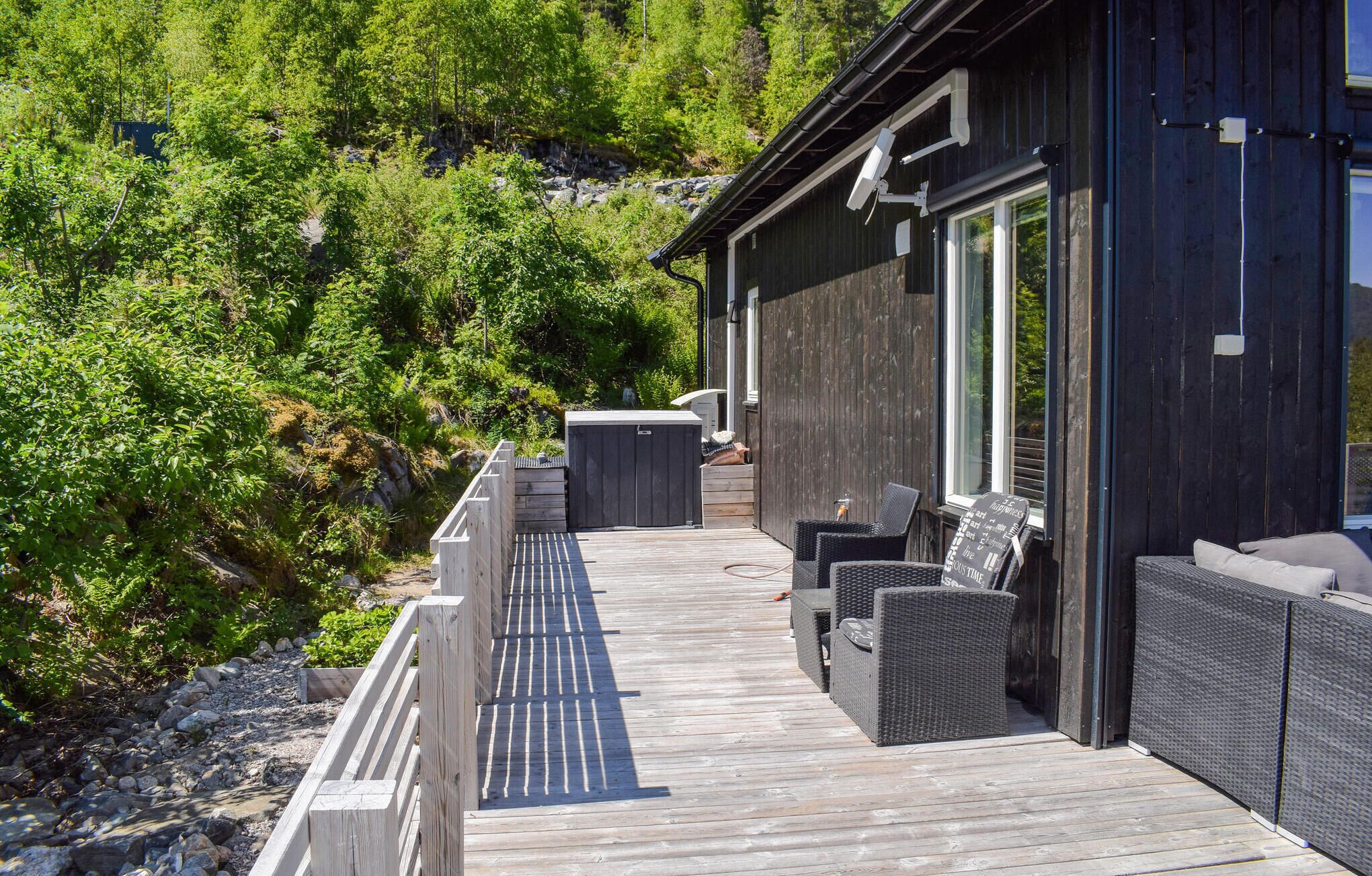 A wooden deck with outdoor seating, a covered area, and a view of a forested hillside.
