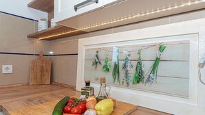 Een keuken met een houten snijplank, verse groenten en kruiden, gepresenteerd op een wandplank.