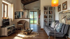 Ein Wohnzimmer mit Fernseher, einem Glastisch, einer Couch und einem Bücherregal.