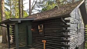Pieni hirsihökkelö, jossa on pieni kuisti ja ovi.