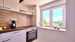 A compact kitchen with a built-in oven, a coffee maker, and a window with a view of greenery. - Stunning home in Samobor (Samobor)
