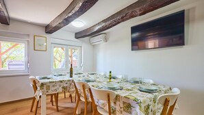 A dining room with a long table set for six, wooden chairs, and a large flat-screen TV mounted on the wall. - Stunning home in Samobor (Samobor)