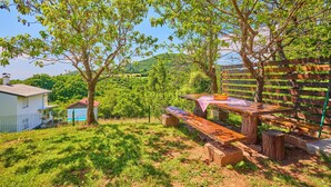 A wooden bench with a table, surrounded by trees and a view of a hillside. - Stunning home in Samobor (Samobor)