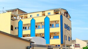 Ein mehrstöckiges Hotel mit Balkonen, Klimaanlagen und einem Schild, das es als Hotel kennzeichnet.