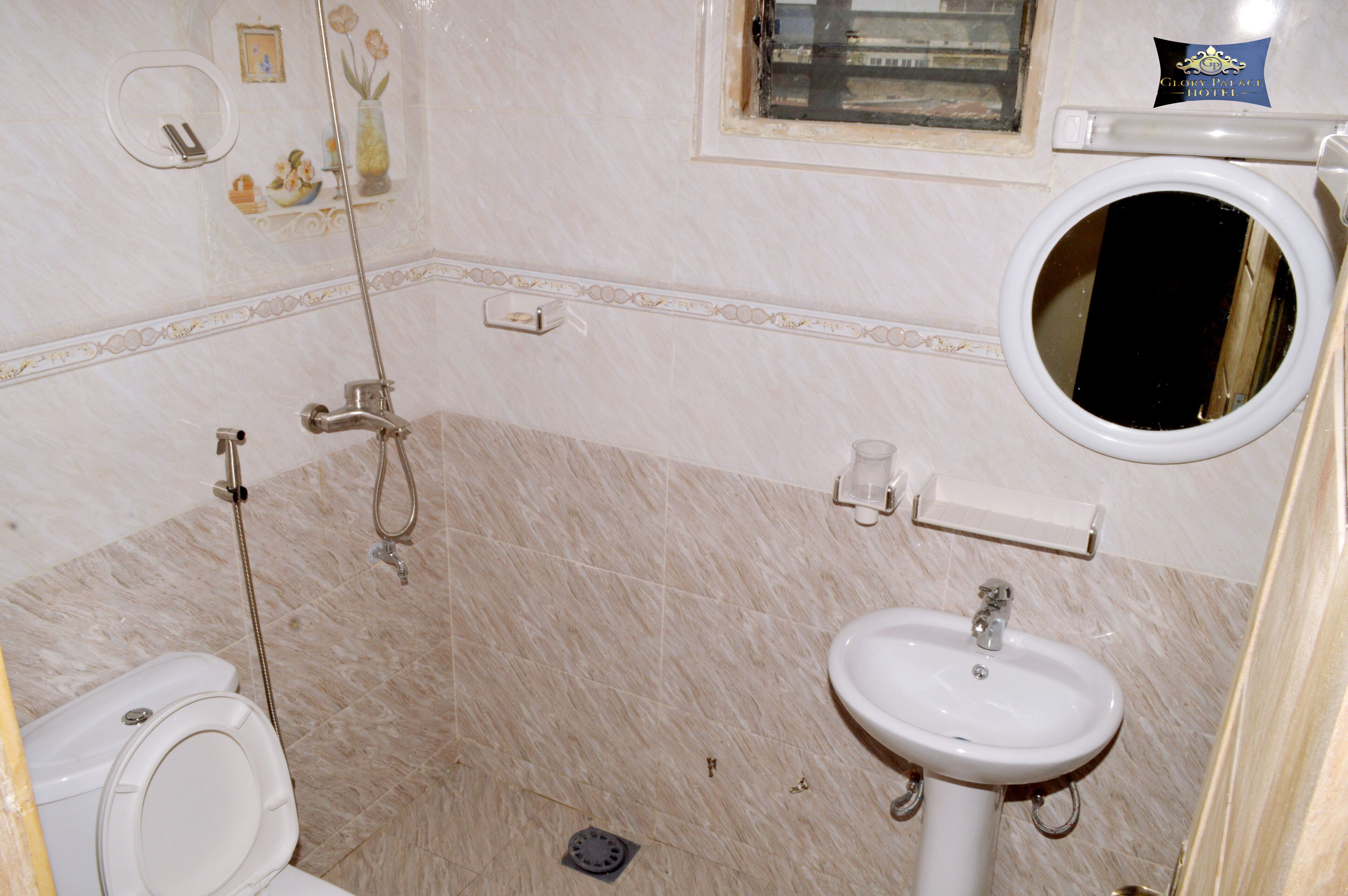 A bathroom with a toilet, sink, shower, and a mirror.