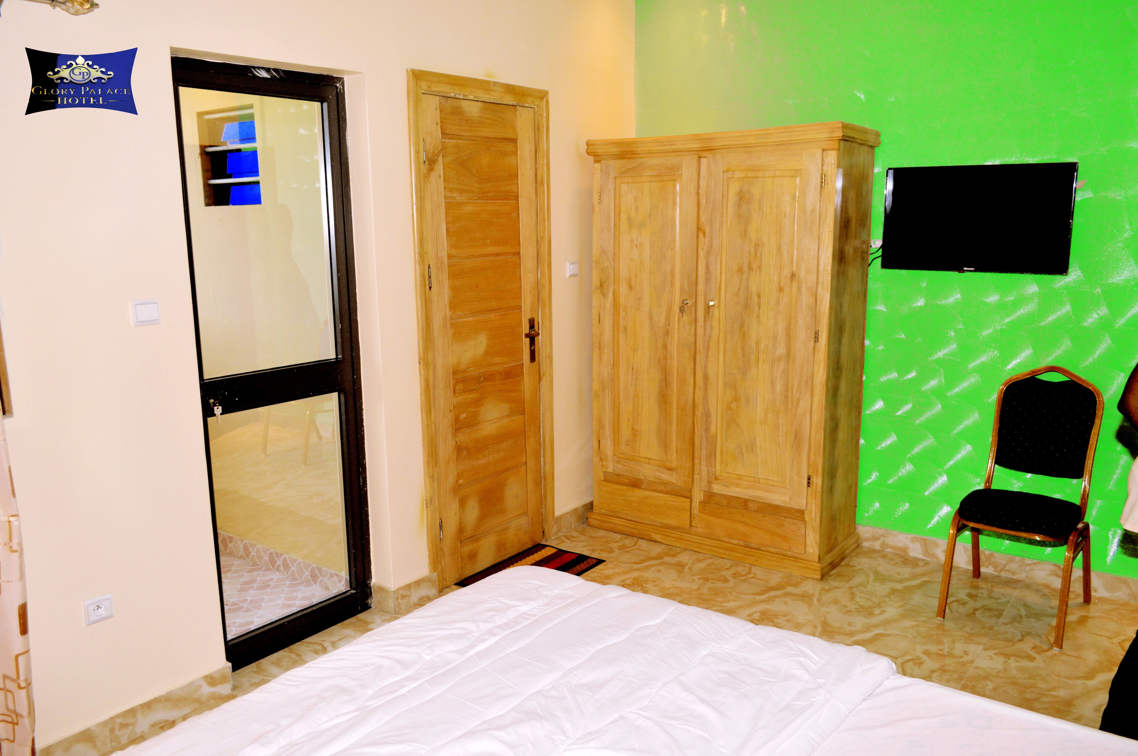 A hotel room with a bed, wardrobe, and a green wall.