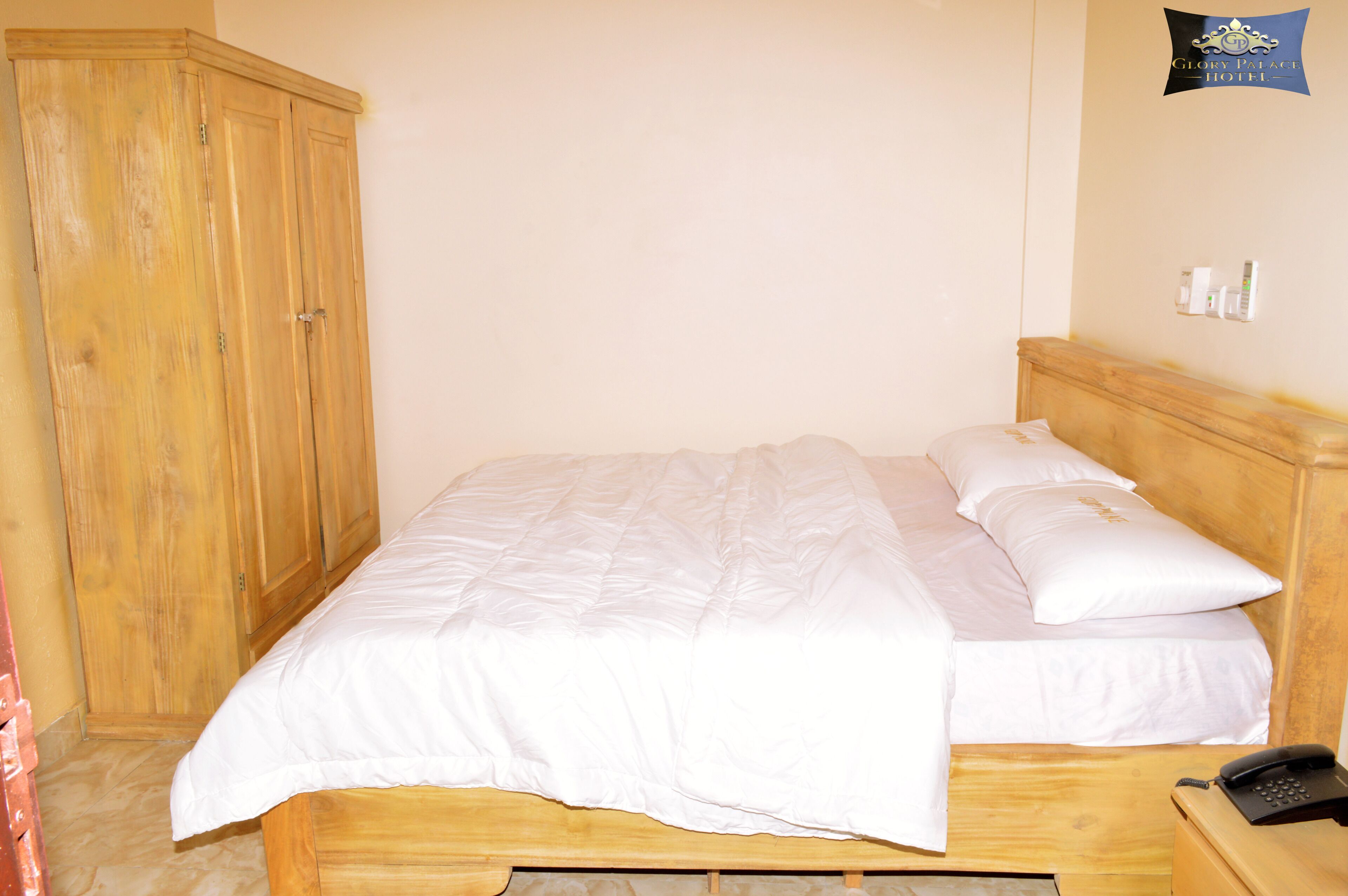 A single bed with white bedding, a wooden headboard, and a bedside telephone.