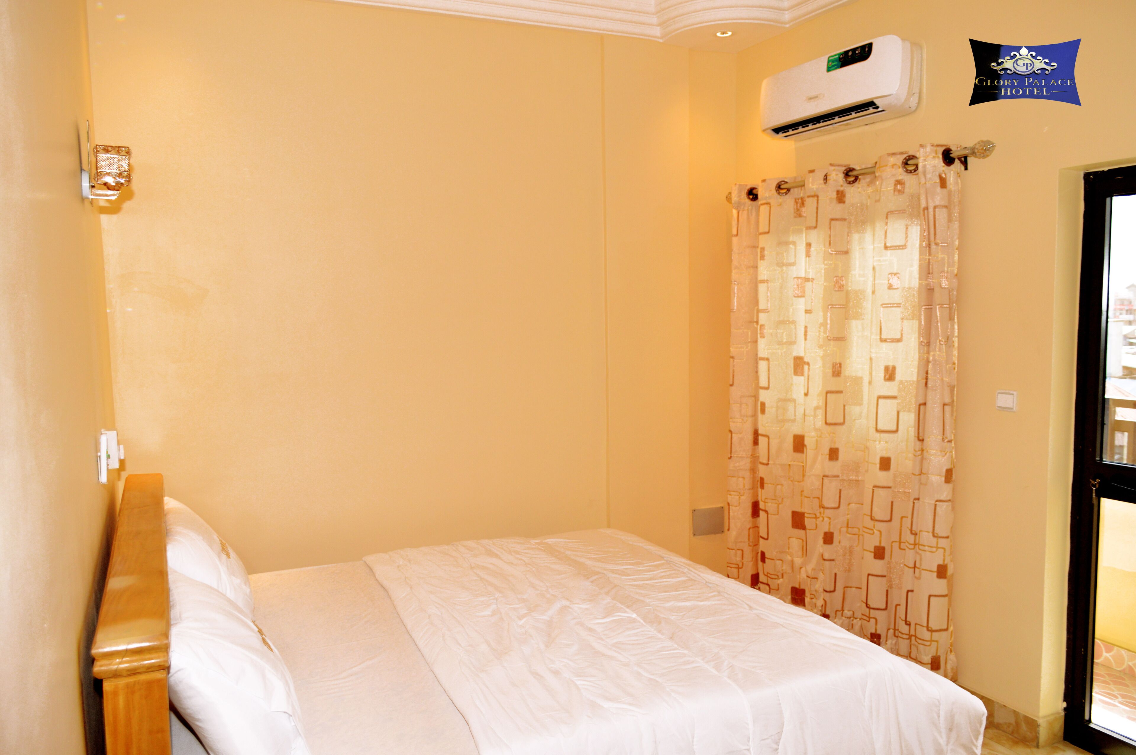 Een hotelkamer met een bed, een airconditioning, een gordijn en een bord aan de muur.