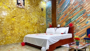 Ein Hotelzimmer mit Bett, einer Wand mit Gemälde und einem Tisch mit Blumen.'