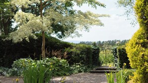 Ein friedlicher Garten mit Teich, üppigem Grün und vielfältigen Pflanzen.