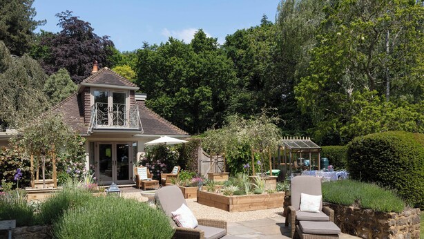 A patio area with wicker chairs and a glass enclosure. - Nest Lodge, a stunning three bedroom lodge surrounded by nature (Pulborough)