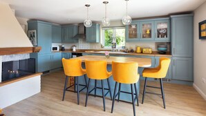 A modern kitchen with blue cabinets, a wooden island, and yellow bar stools. - Nest Lodge, a stunning three bedroom lodge surrounded by nature (Pulborough)